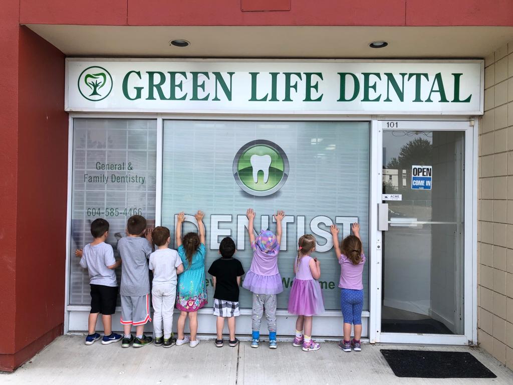 kids standing looking inside window of green life dental in Surrey bc Canada. Dentist in Surrey
