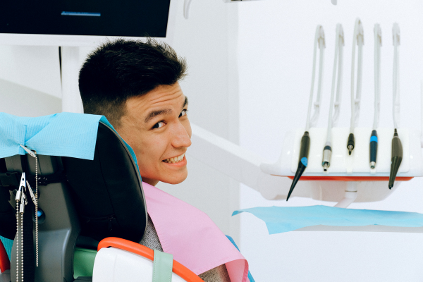 smiling young man in dental chair with dental instruments in the background.
